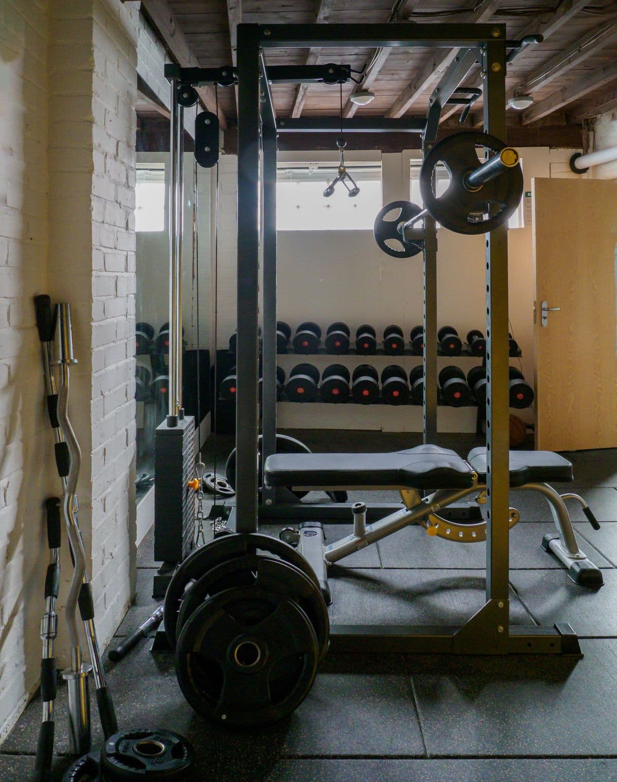 Small room fitted with a bench, weights, and strength-training equipment