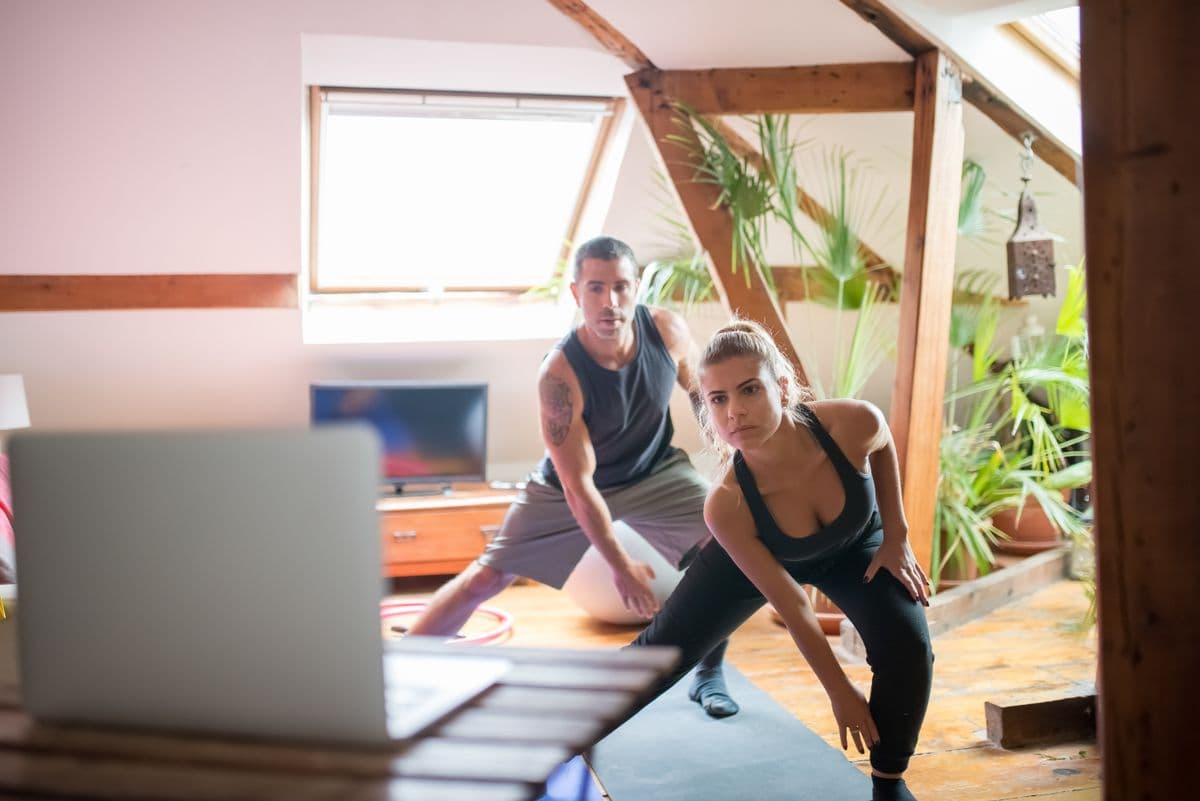 Two people reviewing a guided home workout on a laptop