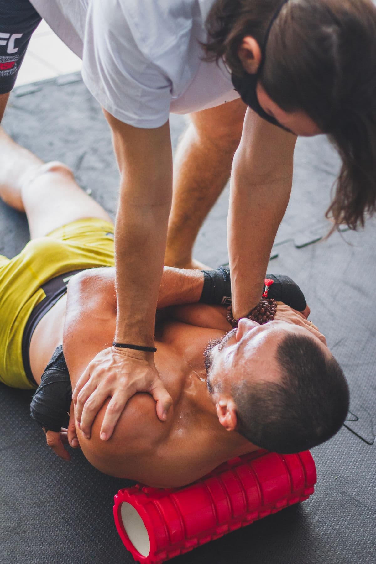 Trainer helping an athlete release muscle tension with a foam roller